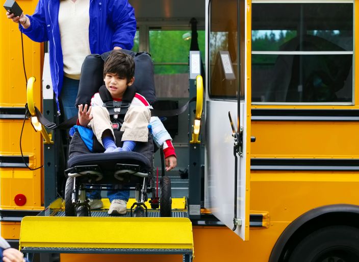 Child on a wheelchair ramp exiting a school bus Child on a wheelchair ramp exiting a school bus