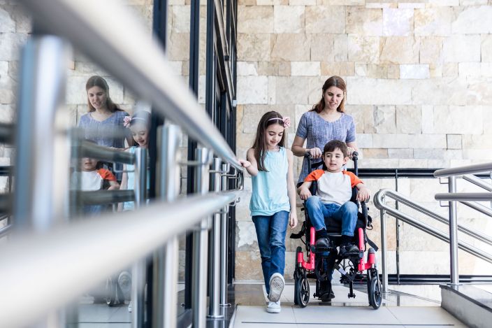 Daughter, mom, and son in a wheelchair on a walkway